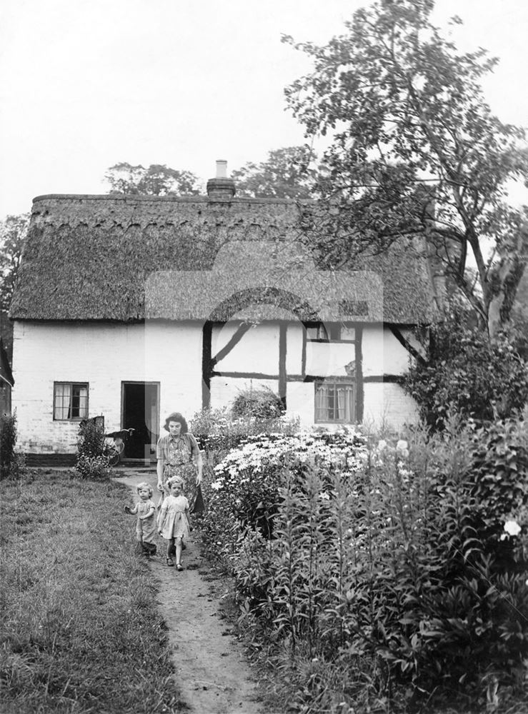 A family in the garden of a timber-framed thatched cottage - Clifton Village