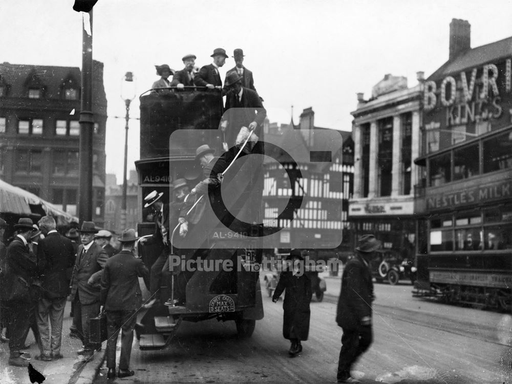 An open topped bus lets passengers off by the Market Place