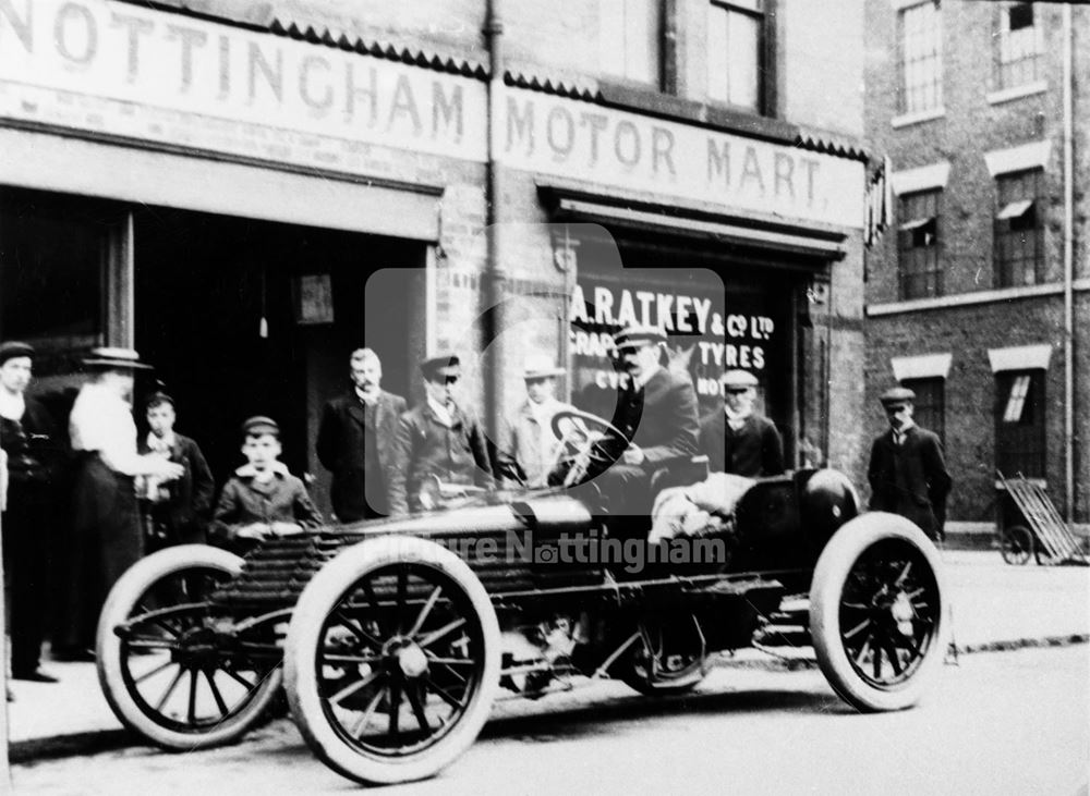 A 50 HP racing Wolsley motor car and spectators outside A R Atkey's Garage